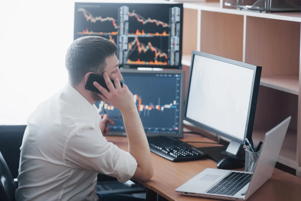 – PU Prime | More Than Trading man looking at monitors with bonds trading chart while being on phone