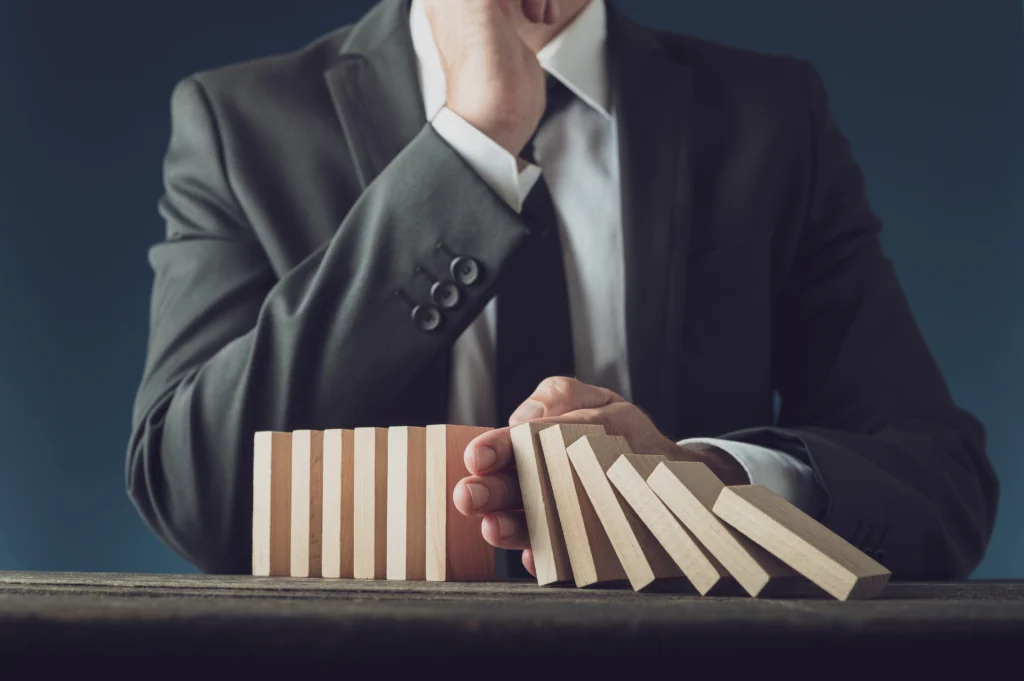 a trader stopping falling dominos from hitting the rest of the wooden blocks, depicting effective trading risk management