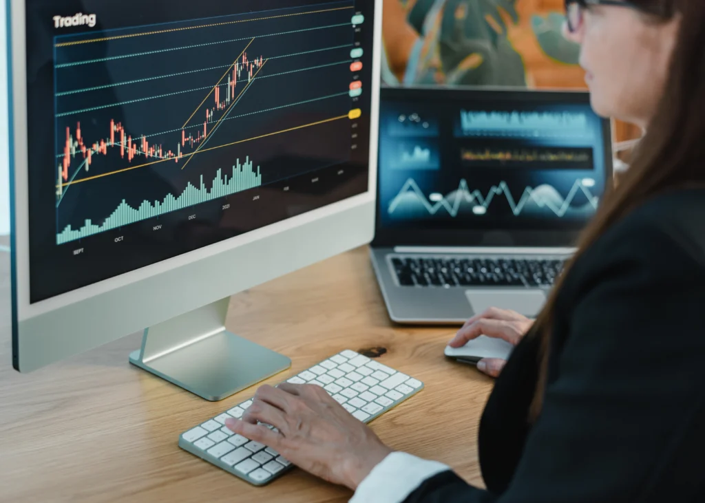 trader using indices trading strategies on a computer monitor and a laptop