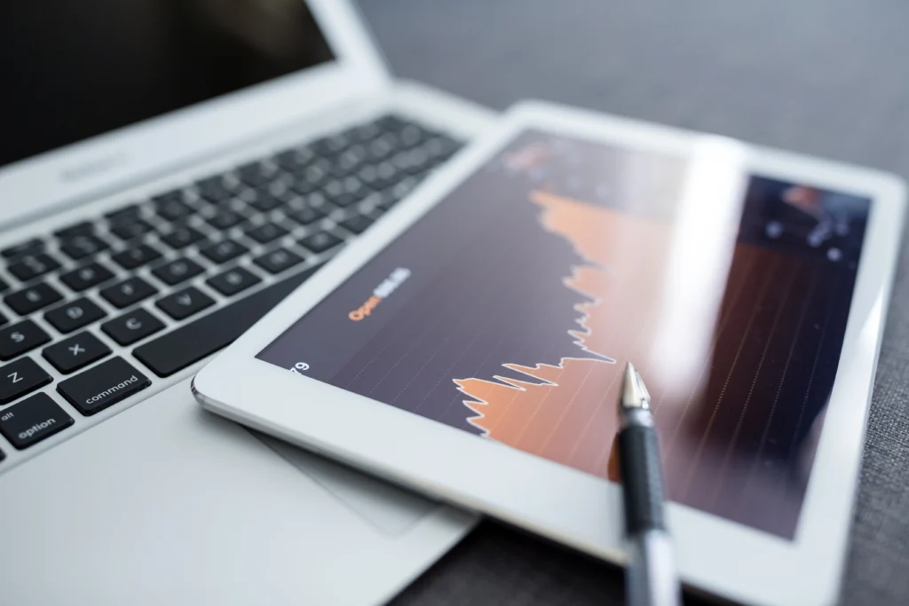 stock market trading chart in a tablet placed above a laptop